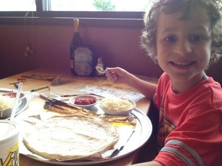 child works on a homemade pizza making kit
