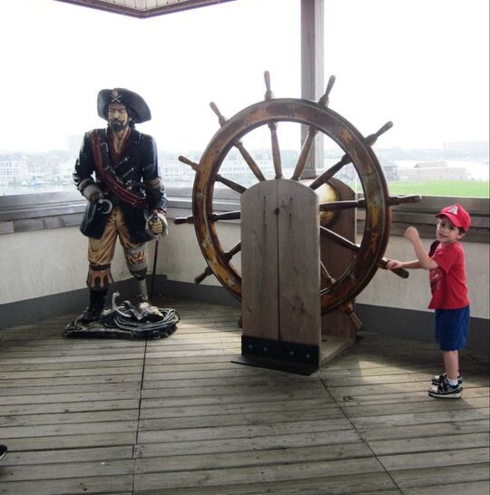 a pirate statue and a boy turning a boar steering wheel on the Widows walk at AC aquarium 2011