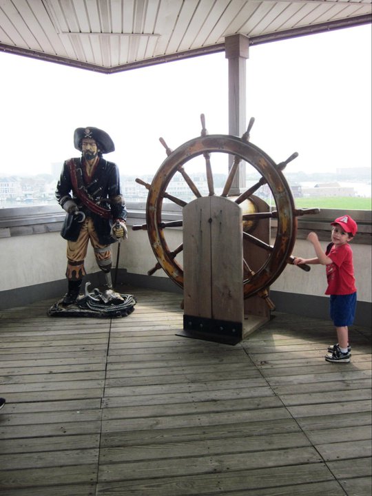 a pirate statue and a boy turning a boar steering wheel on the Widows walk at AC aquarium 2011