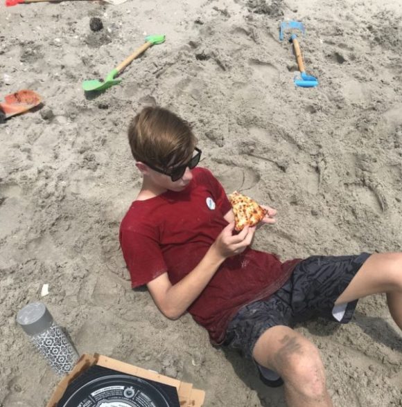 teen on beach eating pizza during a free beach day in Margate NJ