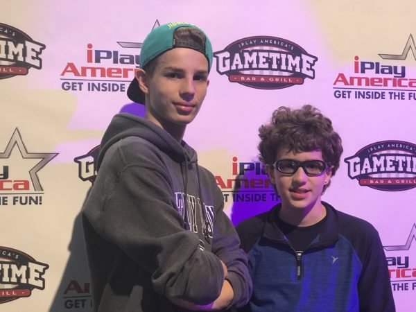 two teenagers in front of the iPlay America backdrop
