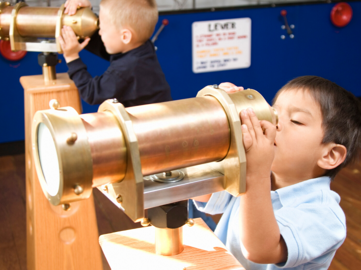 children look through a telescope in a museum