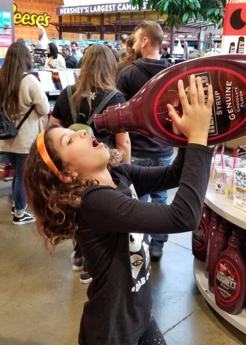 Girl in Hershey's Chocolate World pretending to drink a bottle of hershey's chocolate syrup