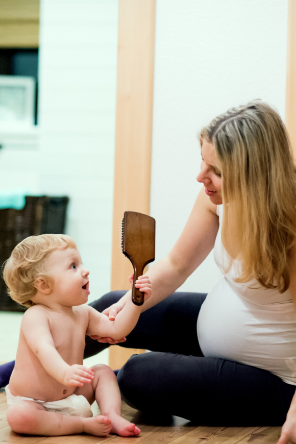 White pregnant mom playing with baby on the floor