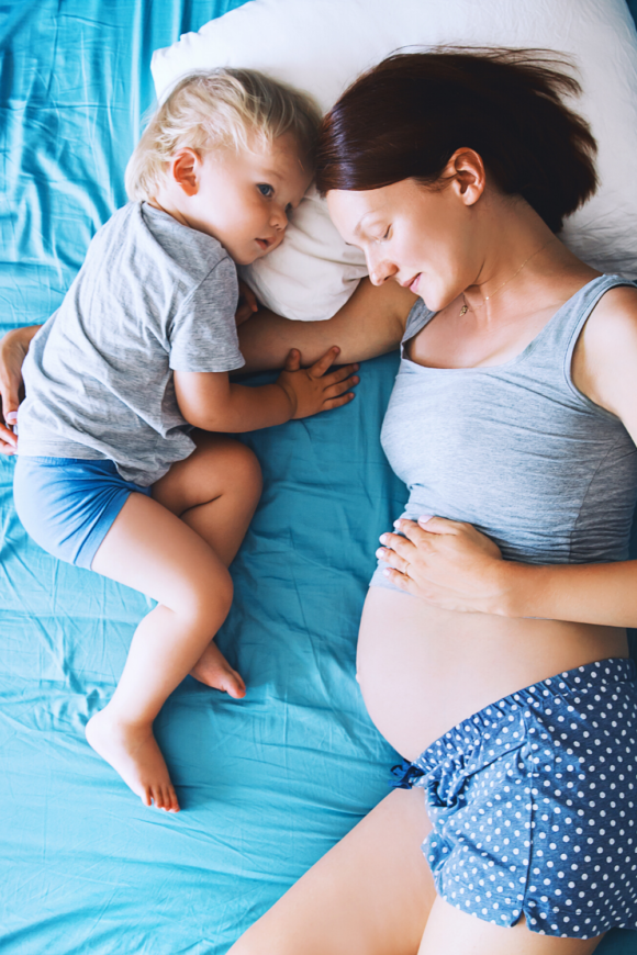 pregnant mother with baby laying in bed