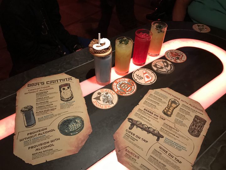 star wars galaxy's edge oga cantina drinks, menu, and coasters on the table.
