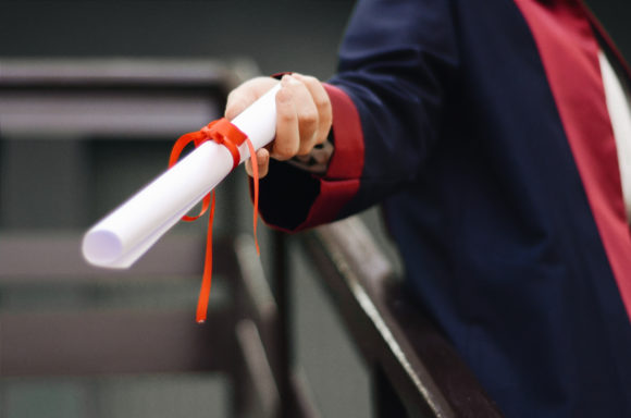 person holding diploma for a drive thru graduation, virtual graduation ideas