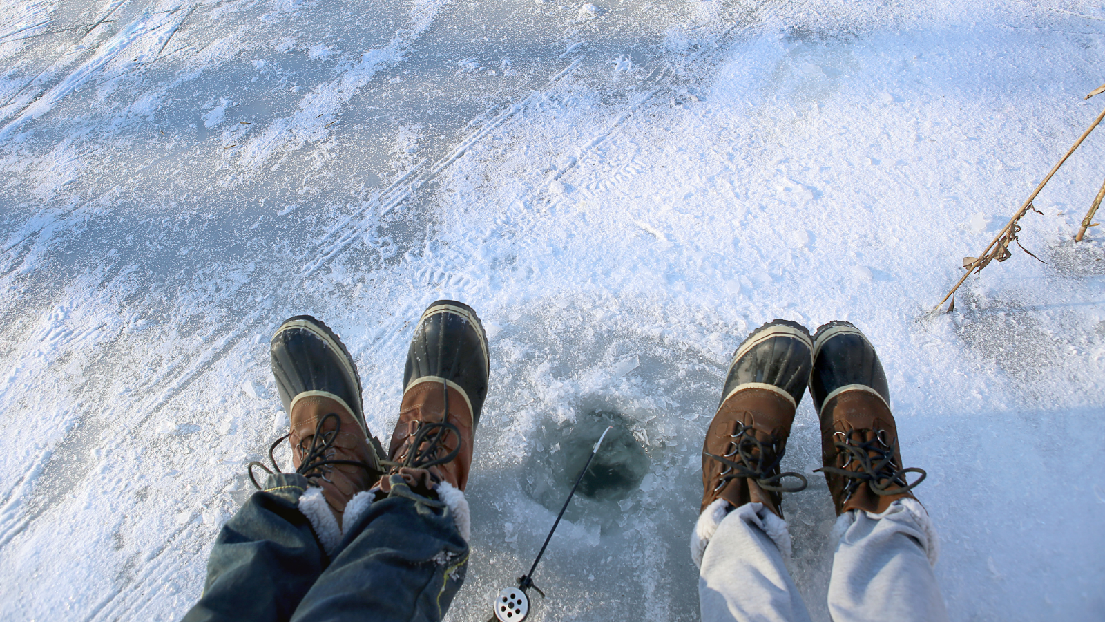 two sets of feet waiting next to an ice fishing spot in New Jersey.