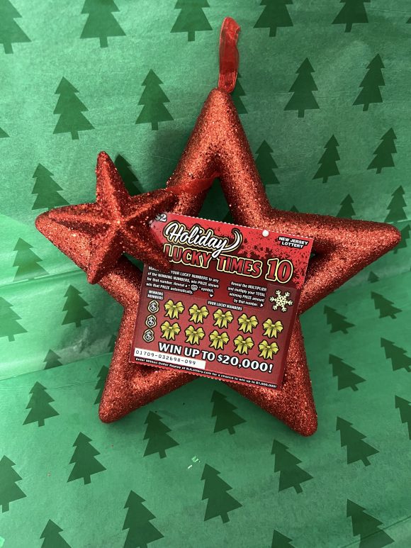 NJ Lottery instant scratch ticket on a red glittery star against a green tissue paper background