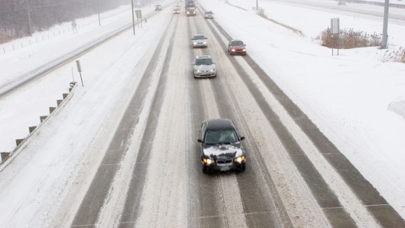 A highway with snowy conditions and cars and trucks