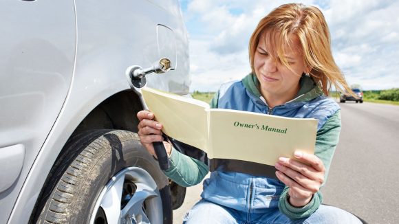 Teen reading car owner manual on the side of the road