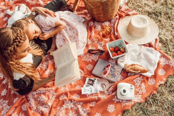 mother and daughter reading together while having a picnic