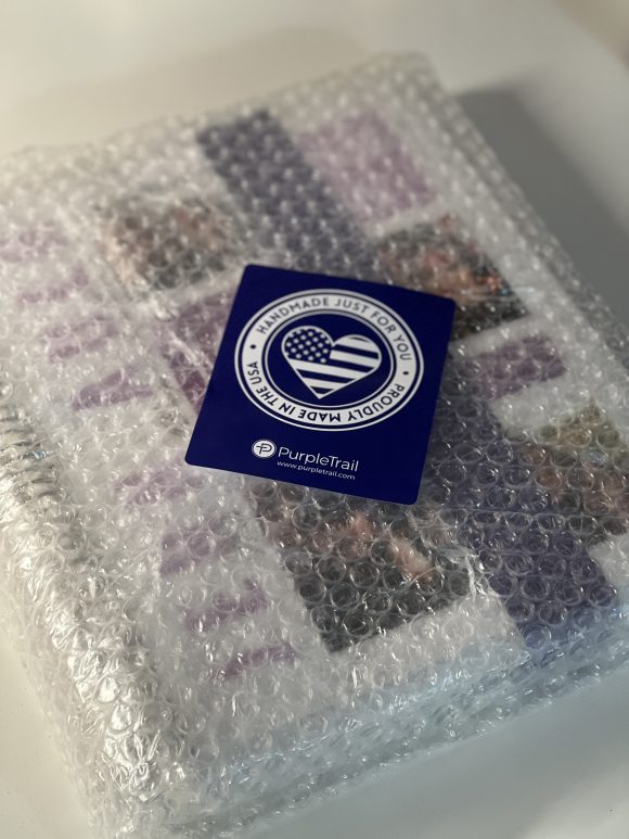 A purple trail planner wrapped in bubble wrap with a made in the usa seal.