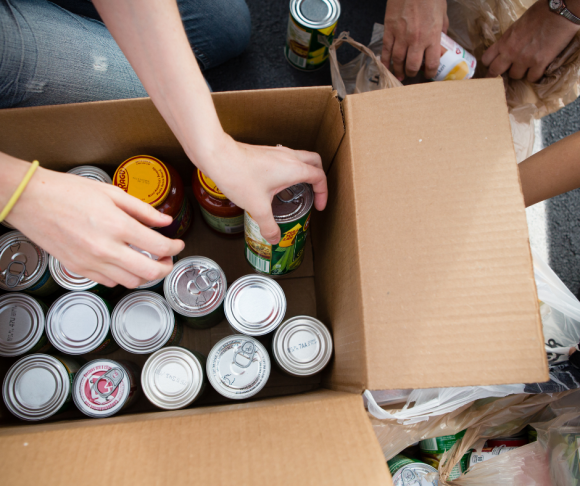 canned goods are being packed into a box at a NJ food pantry