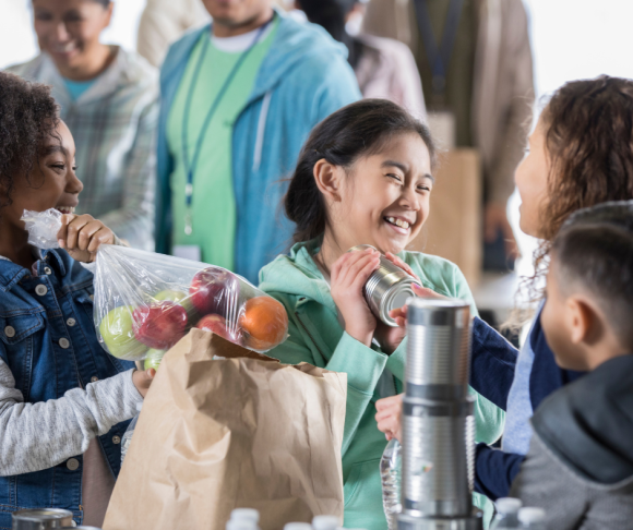 children pack fruit and canned goods from a food drive