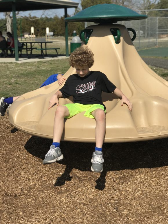 A seated spinner rests on mulch at Bass River Township park playground.
