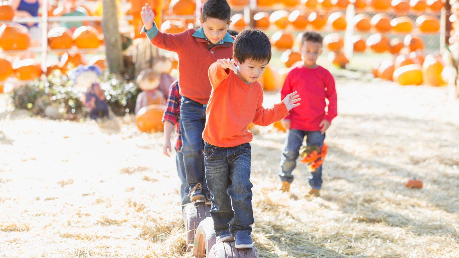 kids-walking-on-tires-with-pumpkins-in-the-background