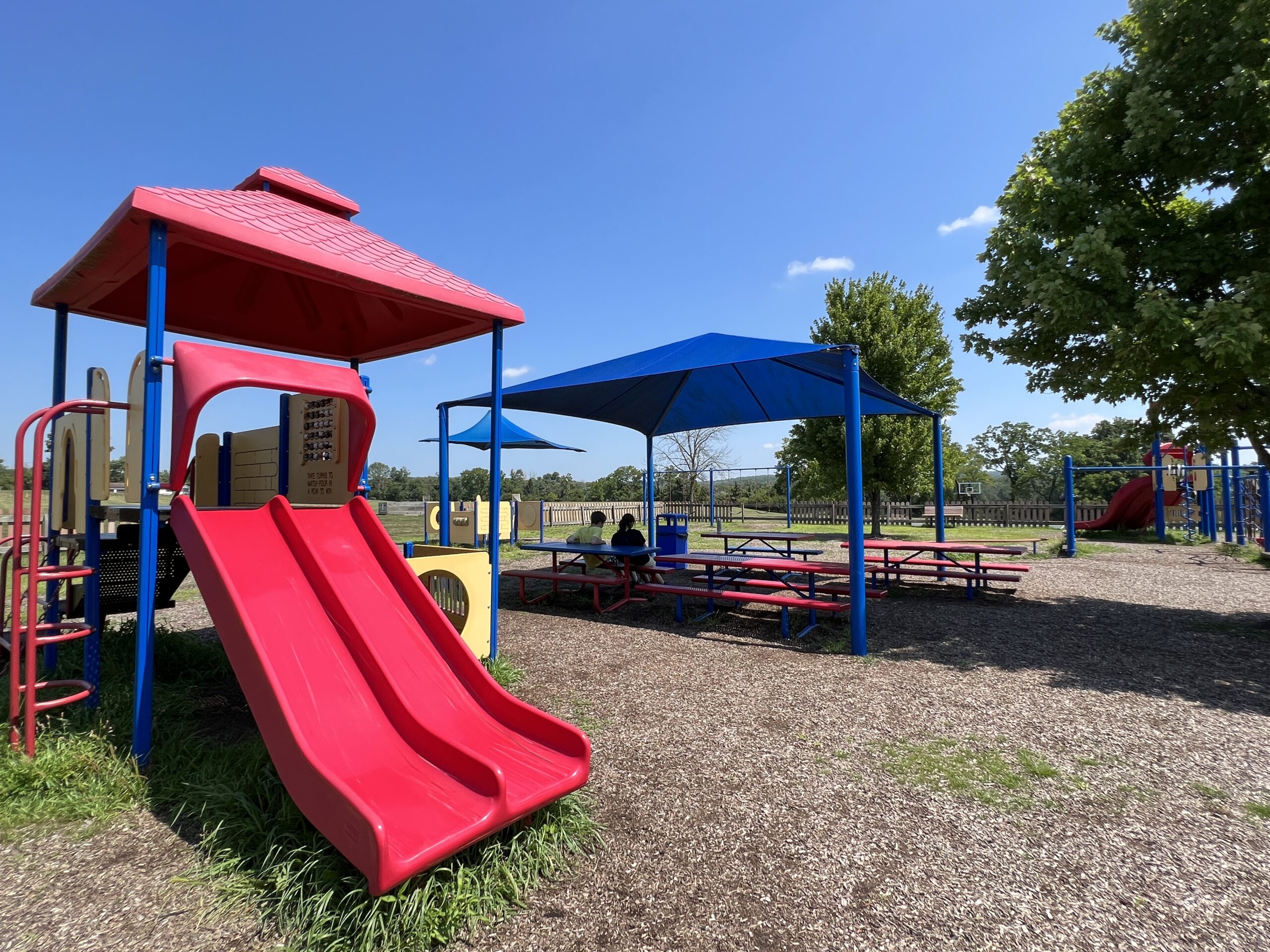 Alexandria Township Park Playground in Milford NJ - WIDE image - red roof playground With picnic tables under canopy SHADY