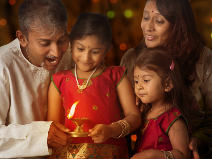 Indian family in traditional sari lighting oil lamp and celebrating Diwali in New Jersey