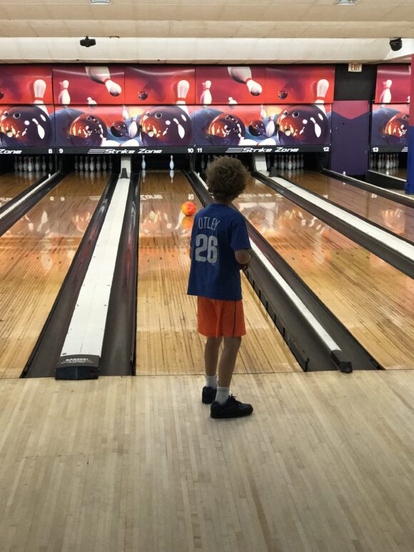 Boy watches bowling ball roll down lane at NJ Bowling Alley near me in Egg Harbor Township