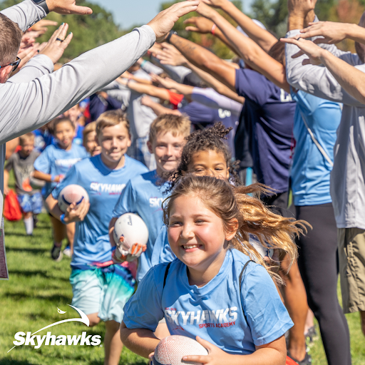 Children run holding a football under the arms of camp counselors at Skyhawks Sports Academy Summer Camp in Cape May Court House South Jersey.